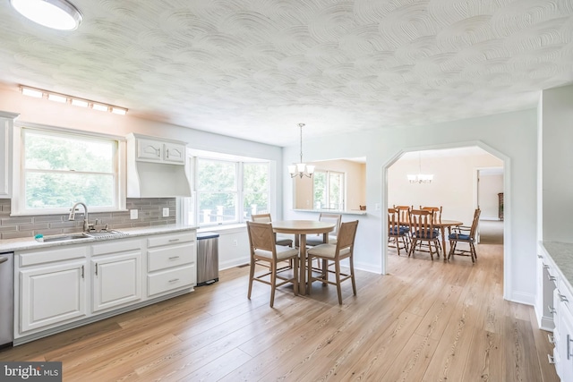 7290 Southern Maryland Blvd, Owings, MD 20736 - kitchen featuring a sink, a chandelier, backsplash, light wood-style flooring, and white cabinetry