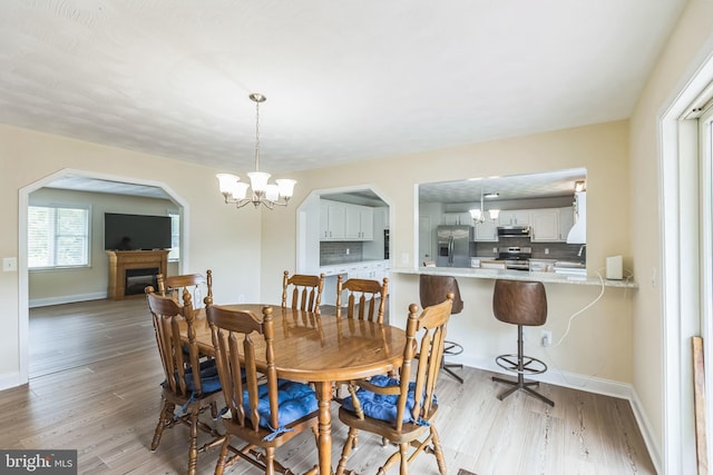7290 Southern Maryland Blvd, Owings, MD 20736 - dining space featuring light wood-style floors, a fireplace, a chandelier, and baseboards