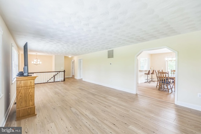 7290 Southern Maryland Blvd, Owings, MD 20736 - unfurnished living room with a chandelier, light wood-style floors, baseboards, and arched walkways