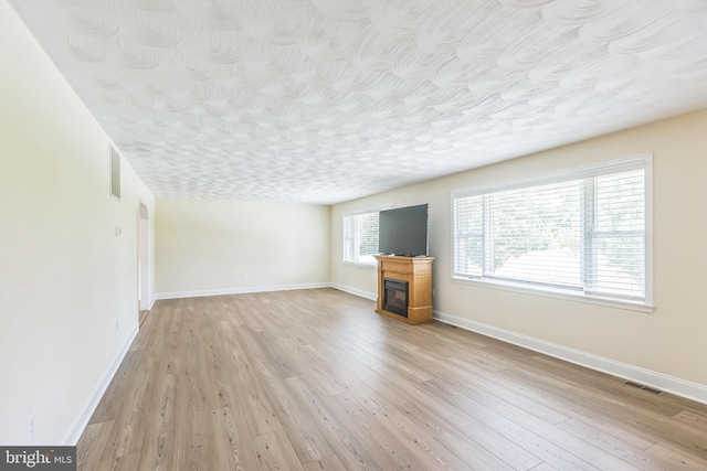 7290 Southern Maryland Blvd, Owings, MD 20736 - unfurnished living room featuring a glass covered fireplace, light wood-style flooring, and baseboards
