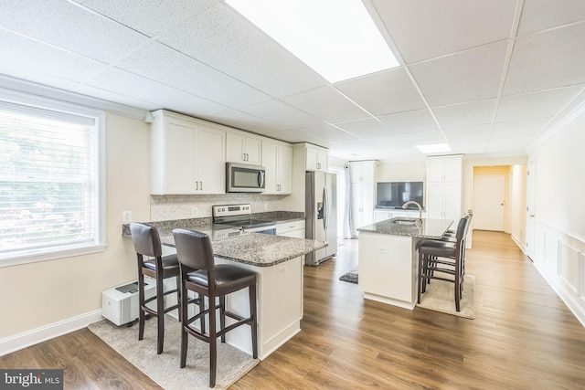7290 Southern Maryland Blvd, Owings, MD 20736 - kitchen with appliances with stainless steel finishes, a kitchen bar, a drop ceiling, white cabinetry, and wood finished floors