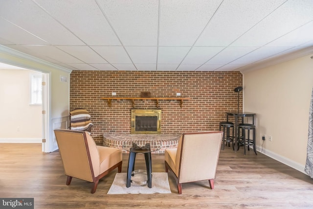 7290 Southern Maryland Blvd, Owings, MD 20736 - dining area with wood finished floors, a fireplace, brick wall, baseboards, and crown molding