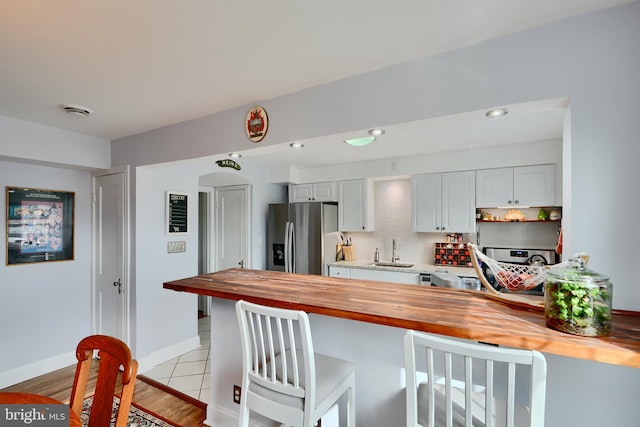 409 Academy Rd, Baltimore, MD 21228 - kitchen featuring butcher block countertops, stainless steel fridge with ice dispenser, a sink, a breakfast bar area, and recessed lighting
