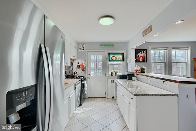 409 Academy Rd, Baltimore, MD 21228 - kitchen featuring appliances with stainless steel finishes, white cabinetry, light tile patterned floors, a peninsula, and light stone counters