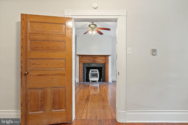 unfurnished living room featuring a ceiling fan, wood finished floors, and baseboards