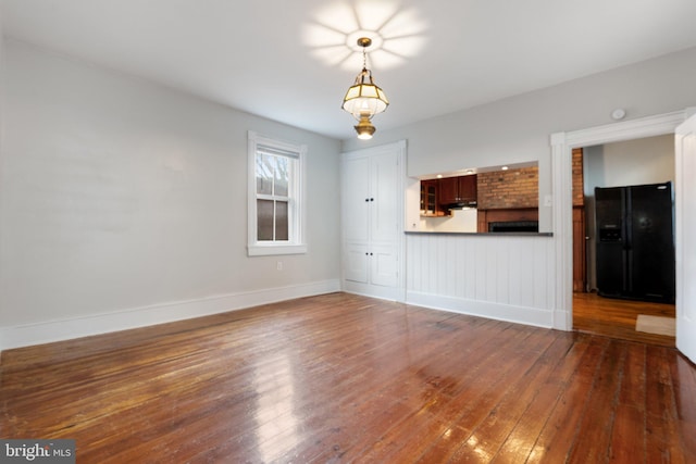 unfurnished living room featuring hardwood / wood-style flooring and baseboards