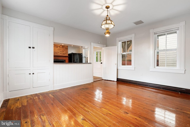 unfurnished living room featuring hardwood / wood-style flooring and a baseboard heating unit