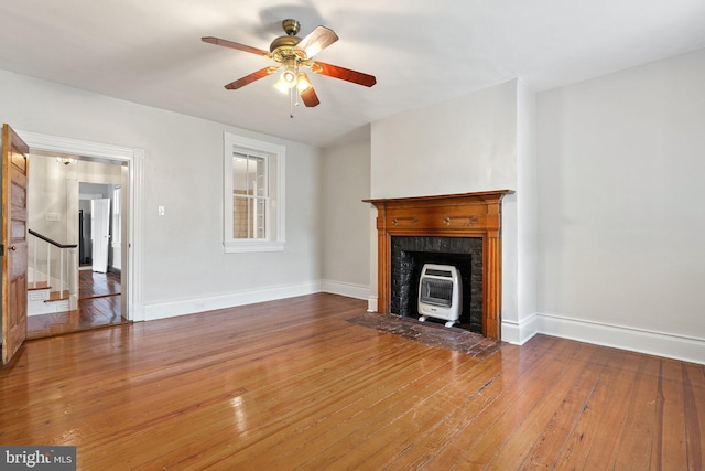 unfurnished living room featuring heating unit, hardwood / wood-style floors, stairs, ceiling fan, and baseboards
