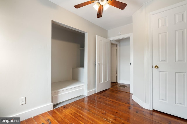 unfurnished bedroom with wood-type flooring, a ceiling fan, and baseboards