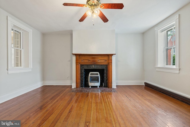 unfurnished living room featuring hardwood / wood-style floors, baseboards, and heating unit