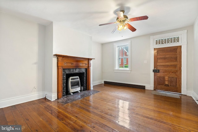 unfurnished living room featuring wood-type flooring, ceiling fan, baseboards, and heating unit