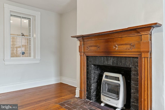 detailed view of heating unit, baseboards, and wood finished floors