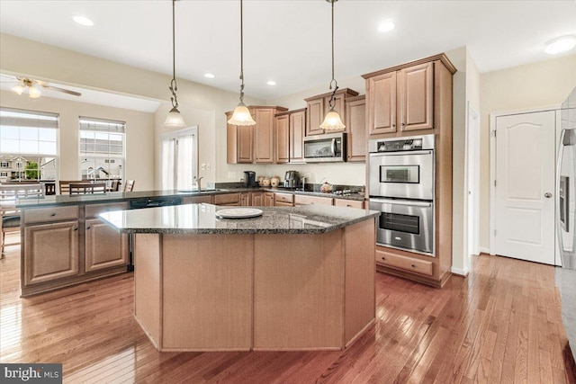 13324 John Martin Dr, Williamsport, MD 21795 - kitchen with a peninsula, dark stone counters, light wood-style flooring, a center island, and appliances with stainless steel finishes