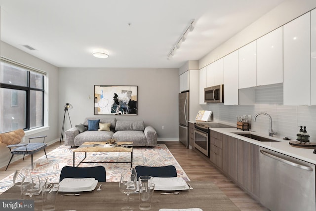 living area with light wood-type flooring, track lighting, and baseboards
