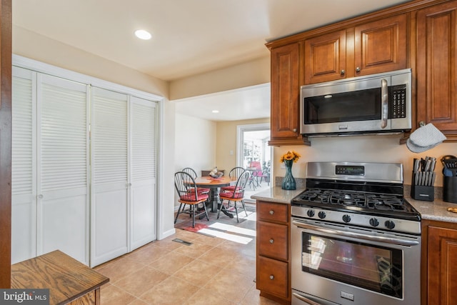 22 N Browning Ave, Somerdale, NJ 08083 - kitchen with stainless steel appliances, brown cabinetry, recessed lighting, light tile patterned floors, and light stone counters