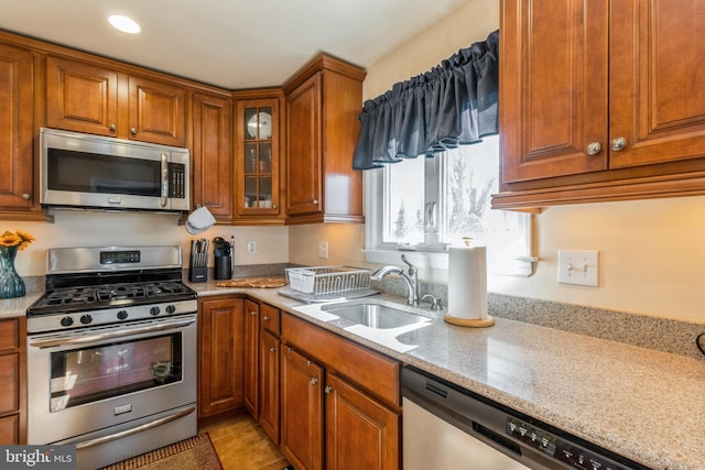 22 N Browning Ave, Somerdale, NJ 08083 - kitchen featuring appliances with stainless steel finishes, brown cabinetry, a sink, light stone counters, and glass insert cabinets