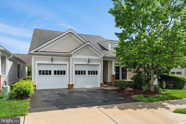 view of front of home featuring driveway, an attached garage, and a shingled roof
