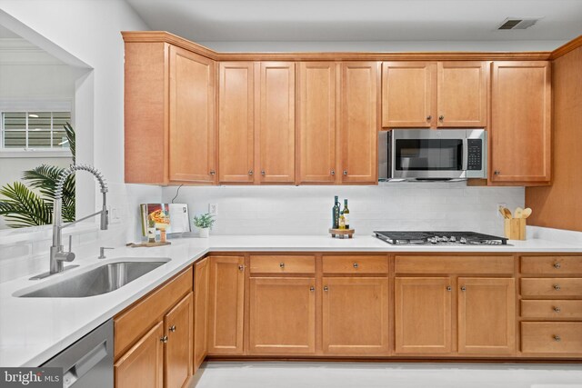 kitchen featuring appliances with stainless steel finishes, a sink, decorative backsplash, and light countertops