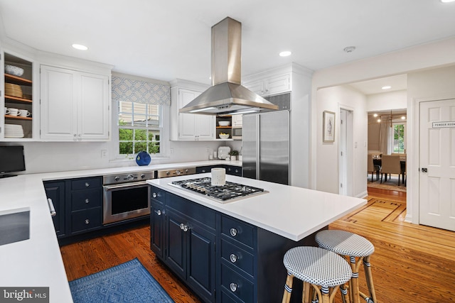kitchen featuring stainless steel appliances, island exhaust hood, white cabinetry, open shelves, and blue cabinets