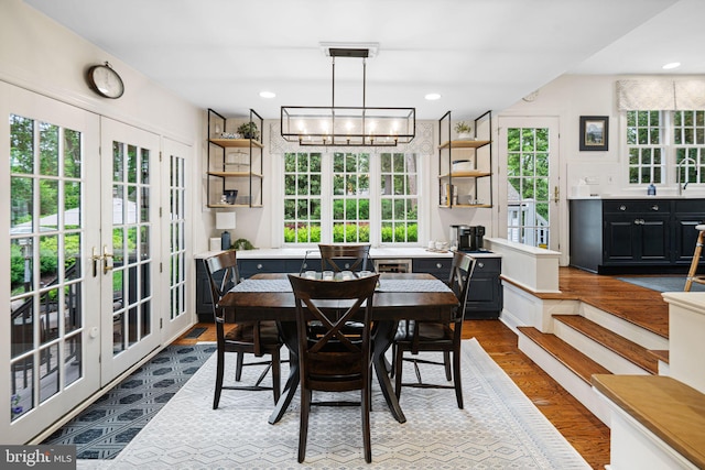 dining area with dark wood-type flooring, french doors, and a chandelier