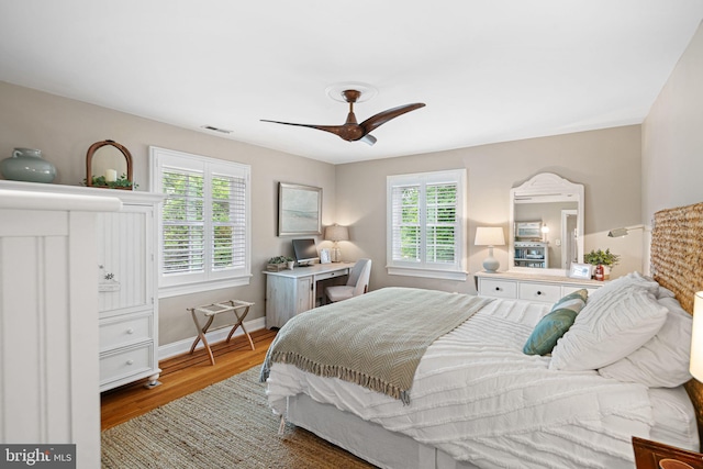 bedroom with multiple windows, wood finished floors, baseboards, and ceiling fan