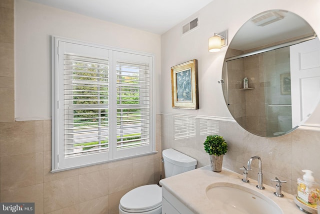 full bathroom featuring tile walls, toilet, tiled shower, and vanity