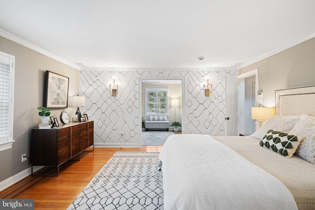 bedroom featuring crown molding, light wood-style flooring, baseboards, and an accent wall