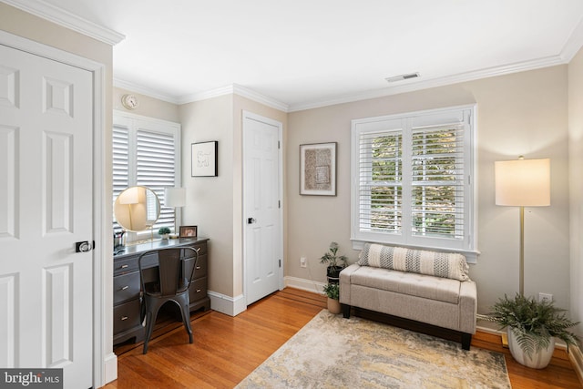 sitting room featuring light wood-style flooring, a desk, baseboards, and crown molding