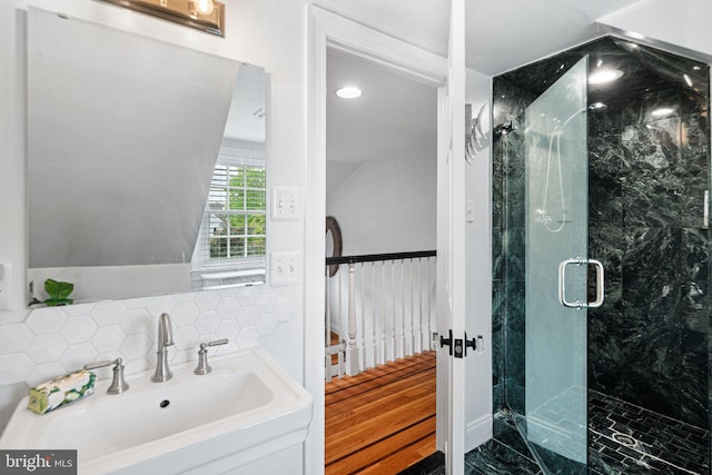 bathroom featuring a sink, a marble finish shower, tasteful backsplash, and recessed lighting