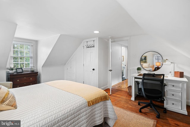 bedroom with wood finished floors, vaulted ceiling, a closet, recessed lighting, and baseboards