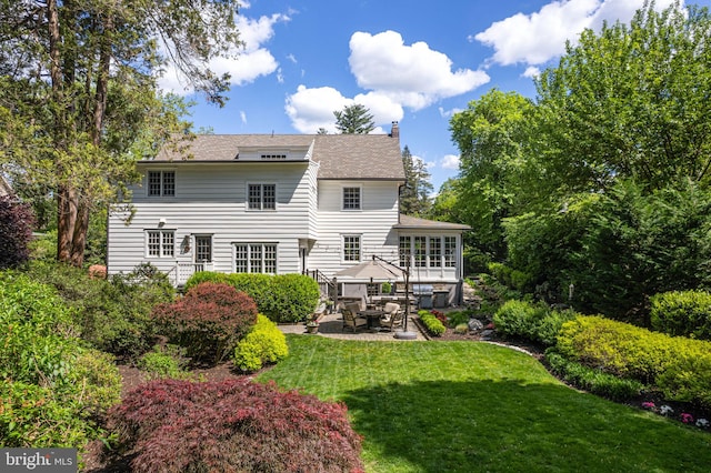 back of property featuring a patio, a chimney, and a lawn
