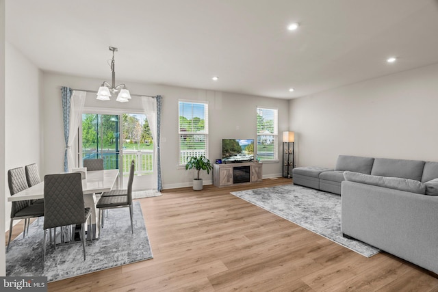 living room with light wood-type flooring, baseboards, an inviting chandelier, and recessed lighting