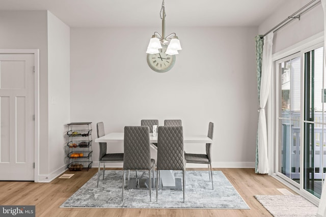 dining area with baseboards, an inviting chandelier, and wood finished floors
