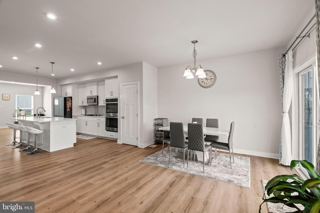 dining area with baseboards, recessed lighting, light wood-style flooring, and a chandelier