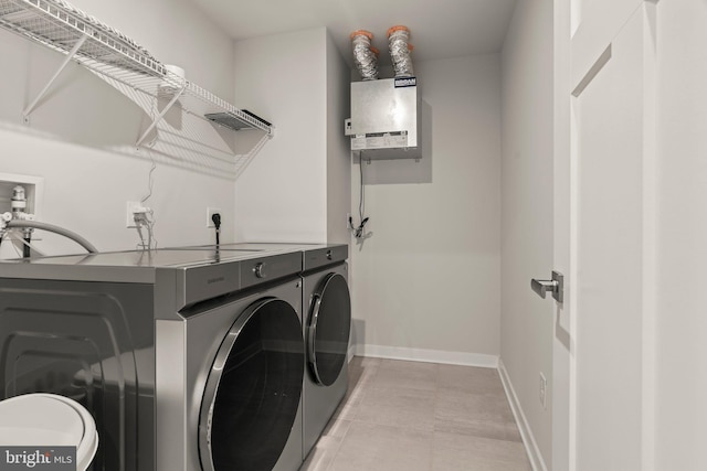 laundry area with baseboards, laundry area, water heater, and washer and clothes dryer
