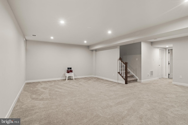 finished below grade area featuring recessed lighting, baseboards, visible vents, stairway, and light colored carpet