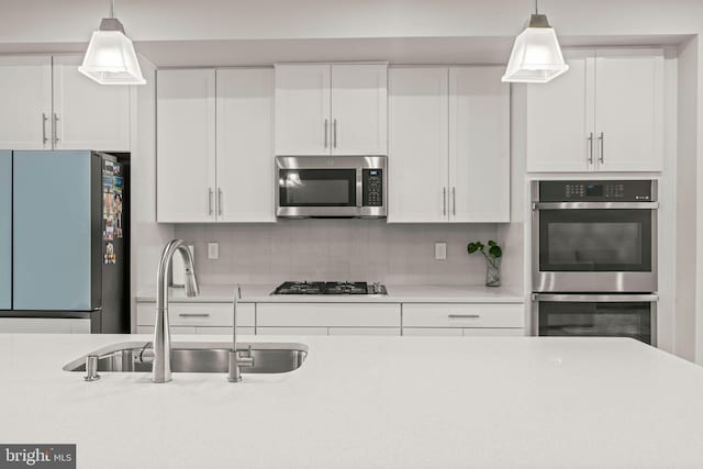 kitchen with decorative light fixtures, tasteful backsplash, a sink, stainless steel appliances, and white cabinets
