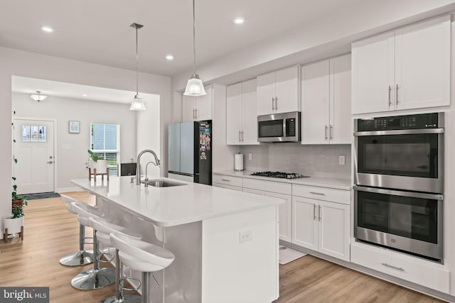 kitchen featuring a sink, recessed lighting, a center island with sink, light wood finished floors, and appliances with stainless steel finishes