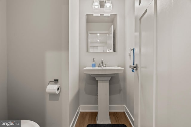 half bath featuring wood finished floors and baseboards