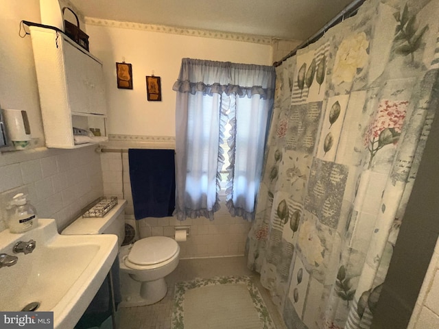 bathroom with tile walls, a sink, toilet, tile patterned flooring, and a shower with shower curtain
