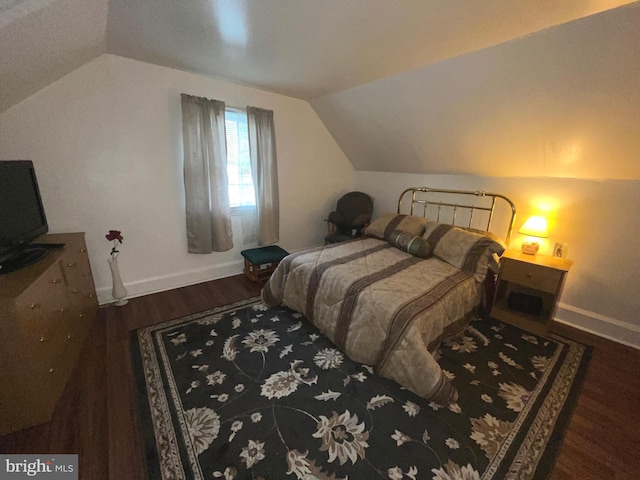 bedroom featuring lofted ceiling, wood finished floors, and baseboards