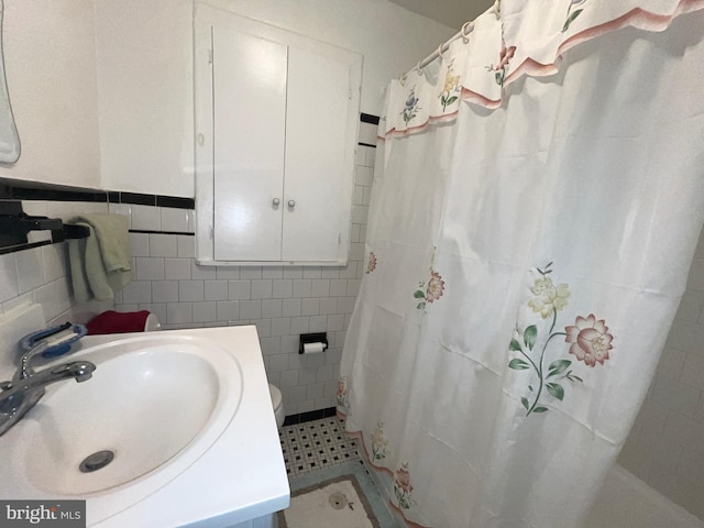 bathroom featuring tile walls, a sink, and a shower with curtain