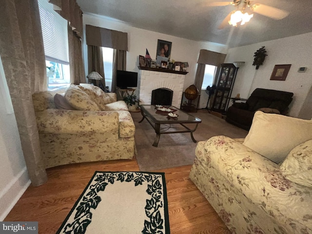 living area featuring wood finished floors, a ceiling fan, and a fireplace