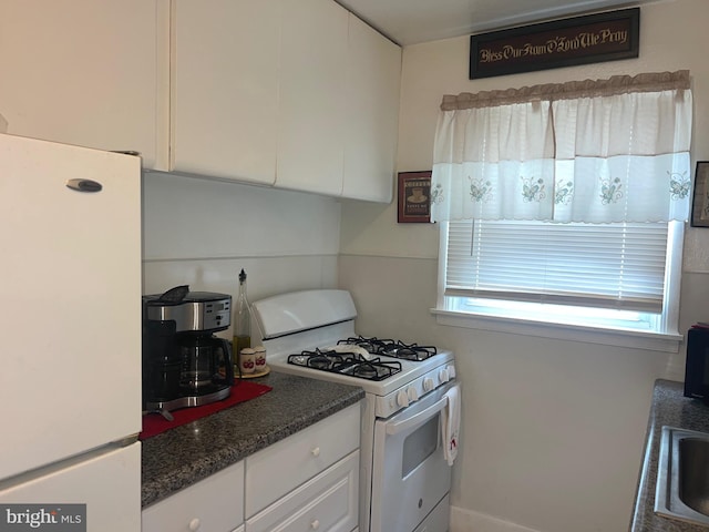 kitchen featuring white appliances, white cabinetry, and a sink