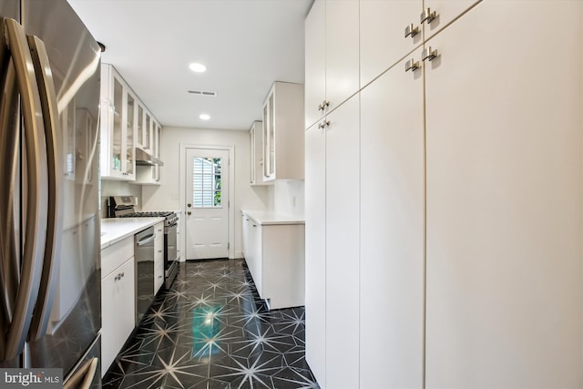 4311 Ellicott St NW, Washington, DC 20016 - kitchen with stainless steel appliances, under cabinet range hood, light countertops, glass insert cabinets, and recessed lighting