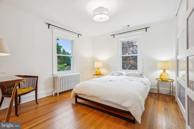 4311 Ellicott St NW, Washington, DC 20016 - bedroom with radiator heating unit, light wood-style floors, and baseboards