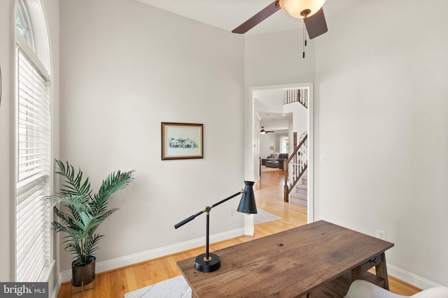 office space with baseboards, light wood-type flooring, and ceiling fan