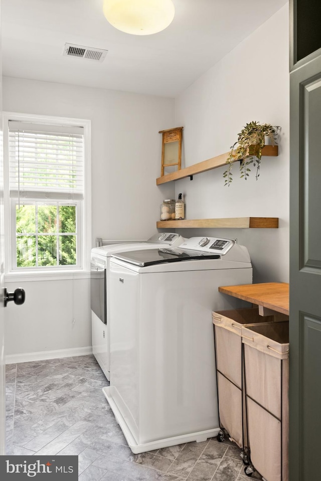 clothes washing area with laundry area, baseboards, independent washer and dryer, and visible vents