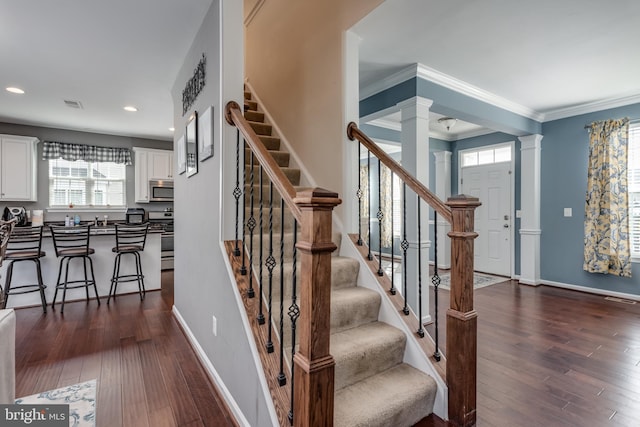 stairs featuring ornate columns, wood-type flooring, baseboards, recessed lighting, and crown molding