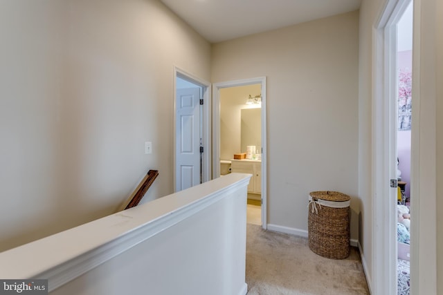 hallway with an upstairs landing, light carpet, and baseboards